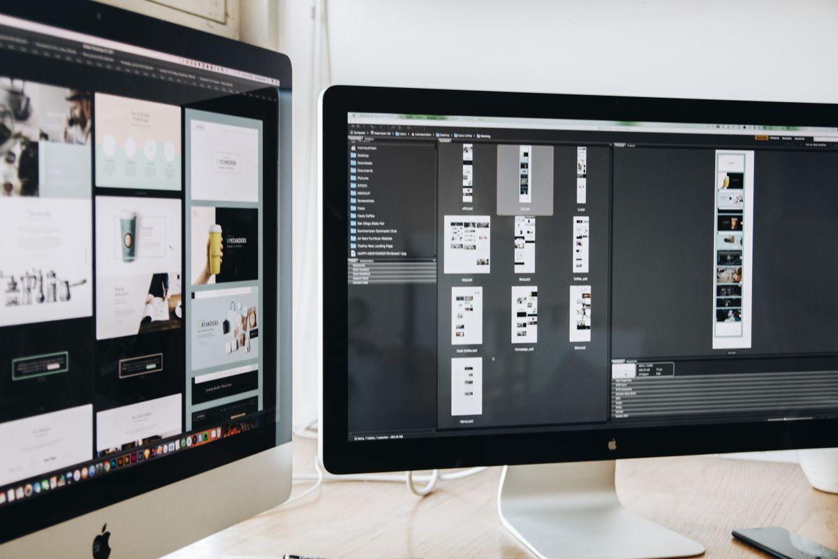 Developer workspace with dual monitors showing website design
